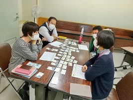 Training scene, four people sitting at a desk playing a card game