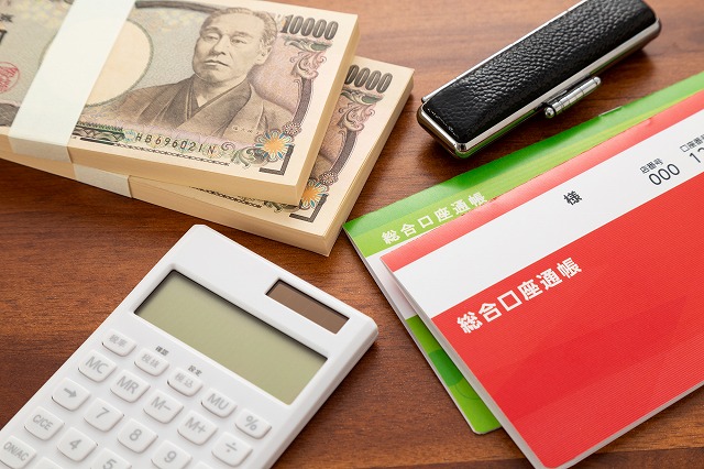 通帳と電卓と１万円の札束の写真