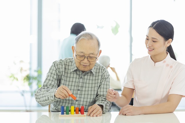 お祖父さんが積み木のようなものでリハビリしている写真