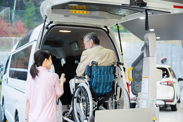 車いすのお祖父さんがリフトで車に乗っている所